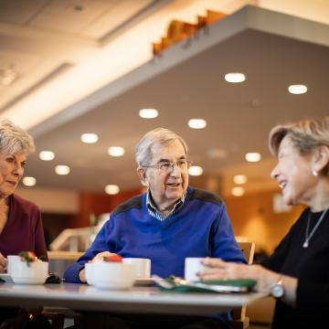 Two women and a man sitting at a table, laughing.